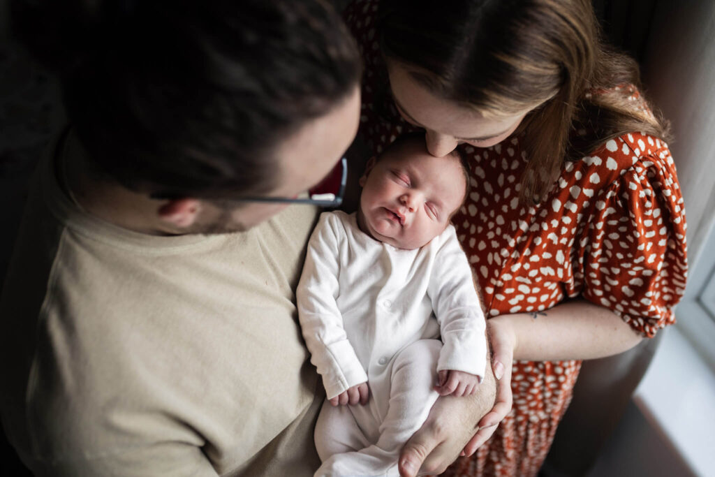 Parents cuddling their newborn baby during a relaxed in-home newborn photoshoot in Glasgow