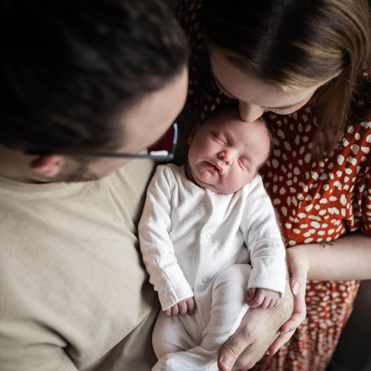 Parents cuddling their newborn baby during a relaxed in-home newborn photoshoot in Glasgow