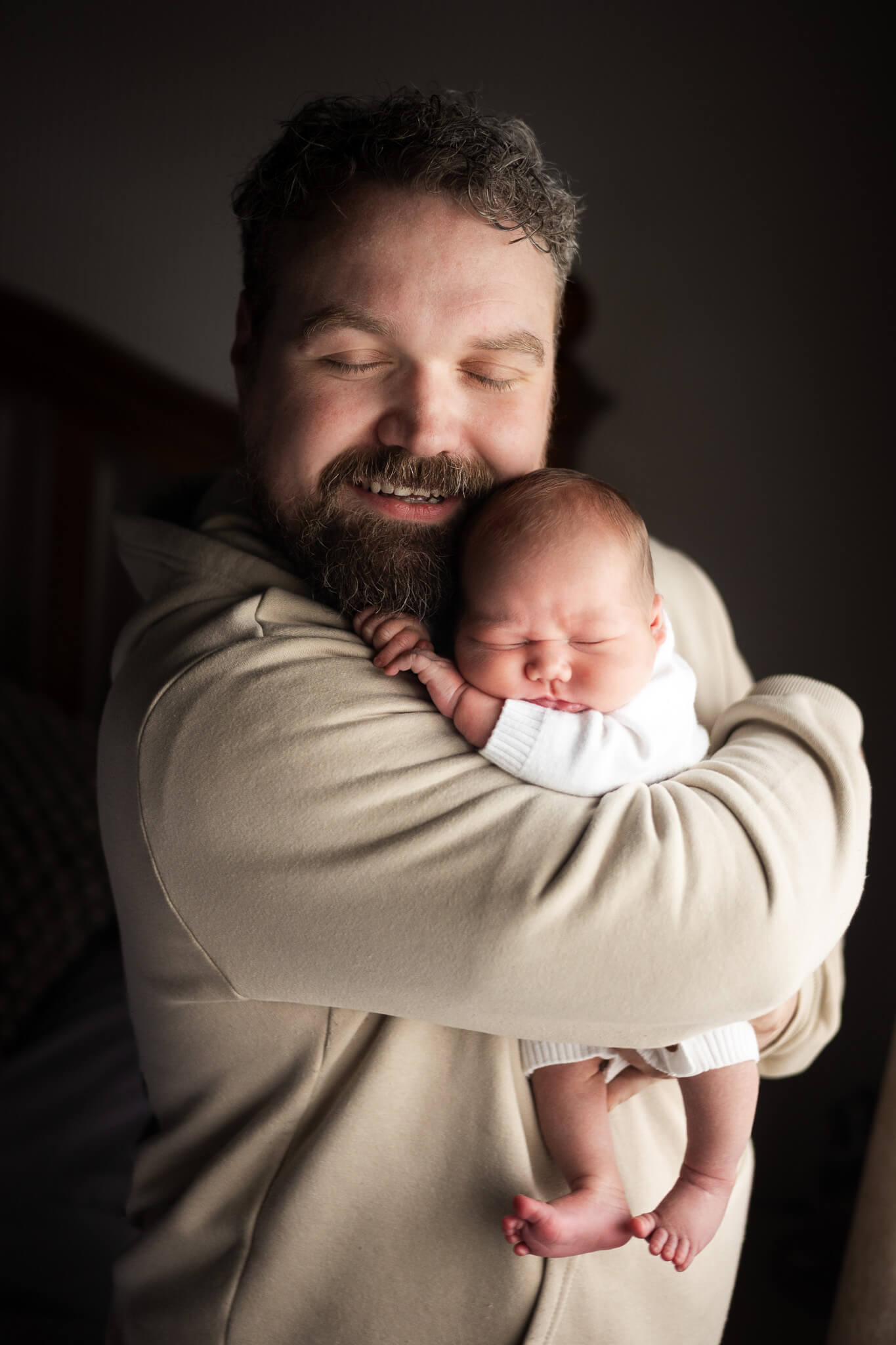 Close-up portrait of father cuddling newborn baby cheek to cheek during lifestyle newborn session