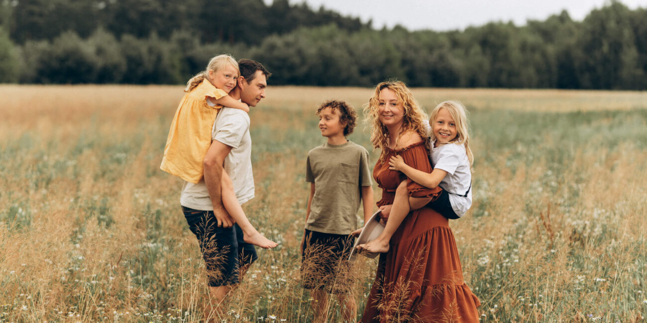 Kinga Szulz and her family during summer session in a wildflower meadow, capturing genuine connection