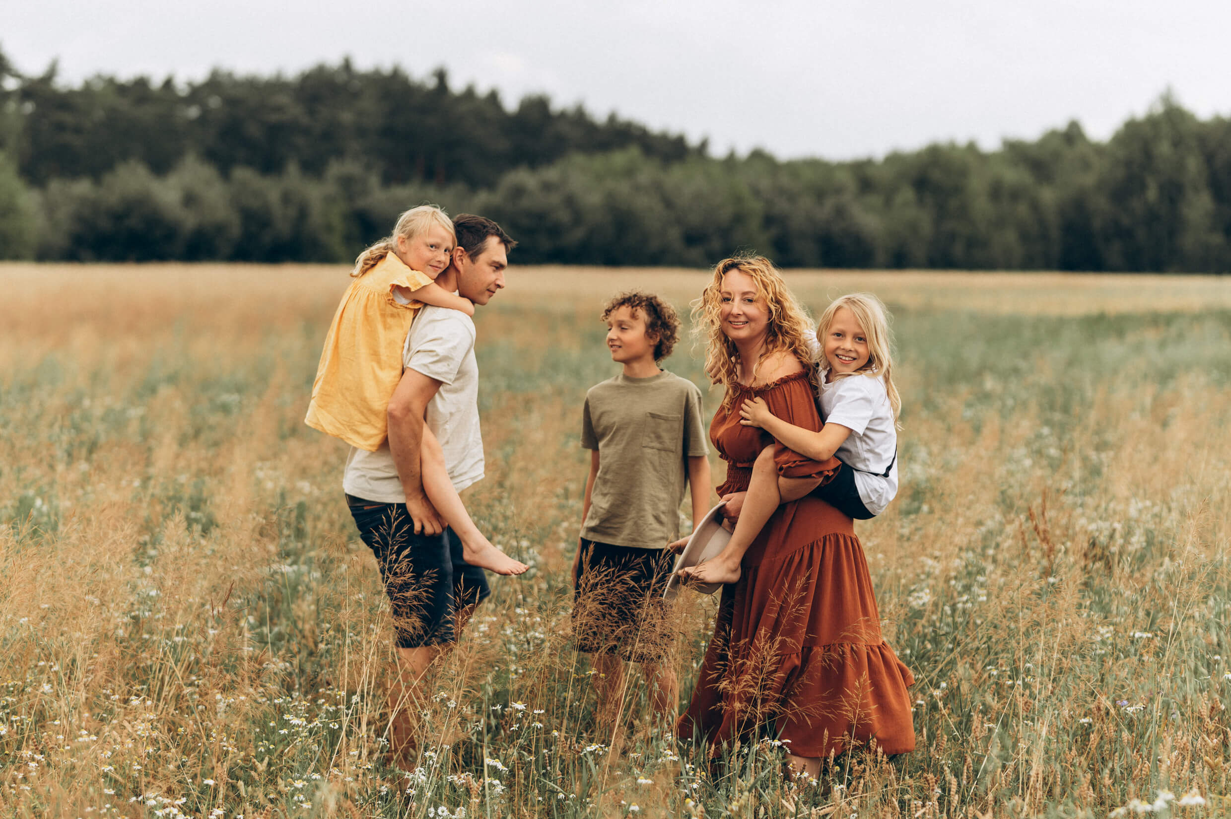 Kinga Szulz and her family during summer session in a wildflower meadow, capturing genuine connection