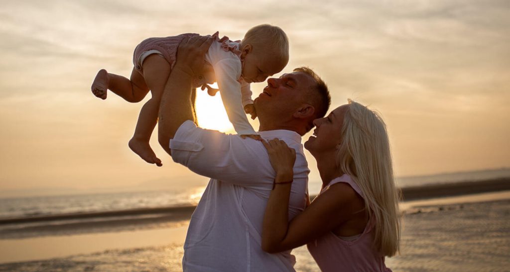 parents lifting their baby on the beach at sunset during a family photoshoot in Scotland