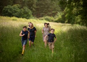 family of five racing in the wild meadow, summer outdoor photoshoot