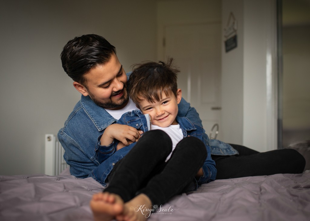 father and son tickling on the bed, family photoshoot at home