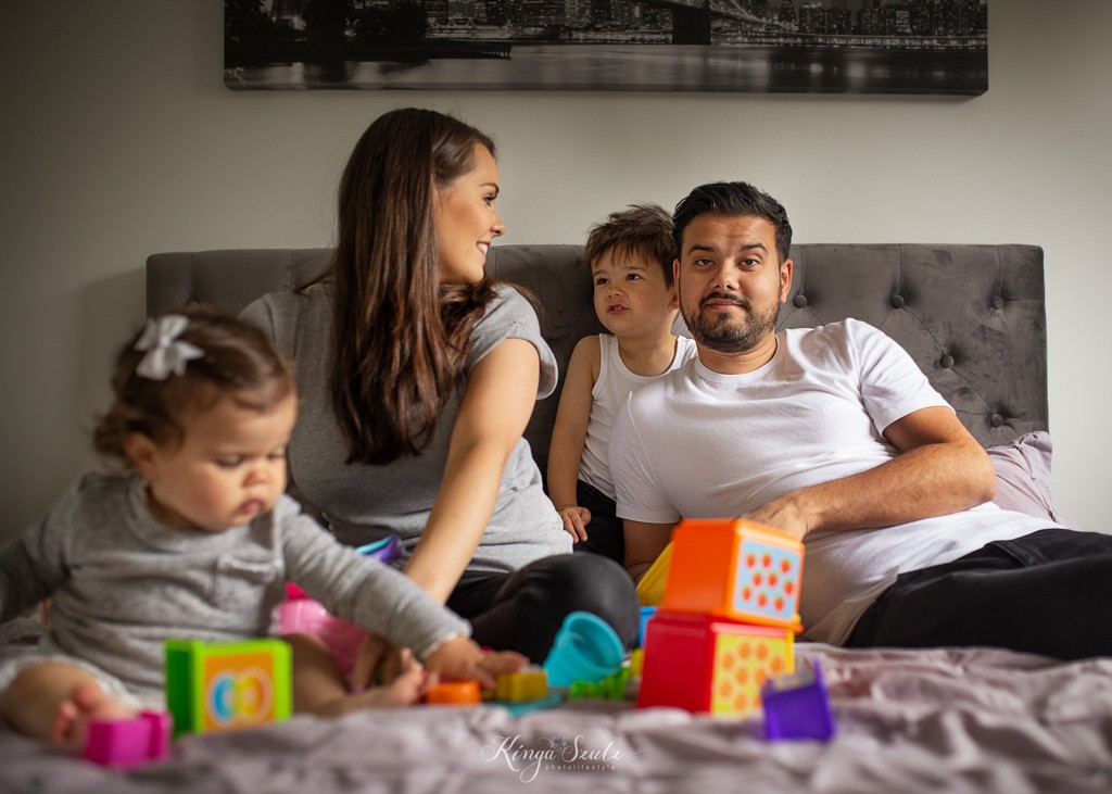 family of four building baby tower toy on the bed, relaxed photoshoot at the home