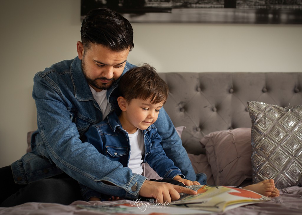 father and son reading book together on the bed, family photoshoot at home