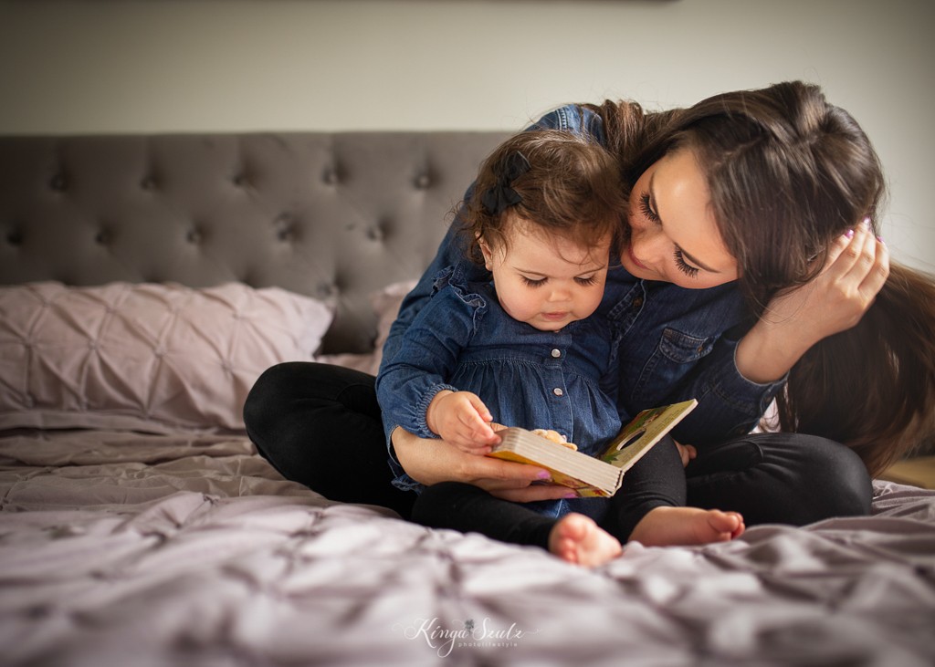 mother and one year old daughter reading baby book, family photoshoot at the home