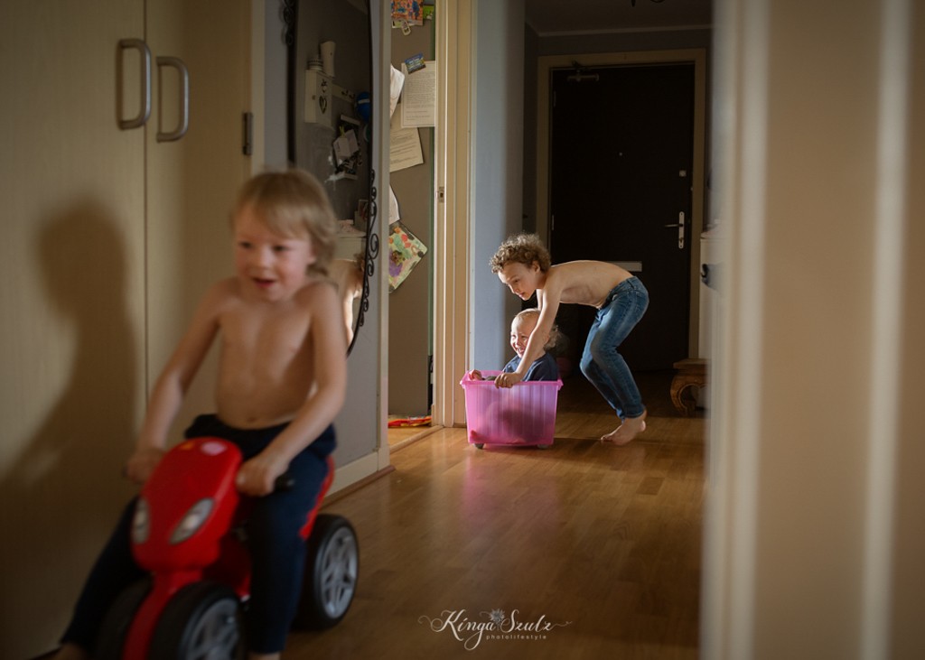 kids ride-in on the hallway in IKEA boxes, in home family documentary photoshoot