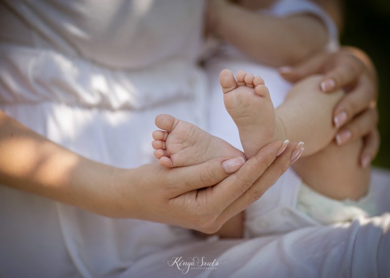 Close-up of newborn baby’s feet resting in their mother’s hands during a summer outdoor newborn photoshoot in Glasgow