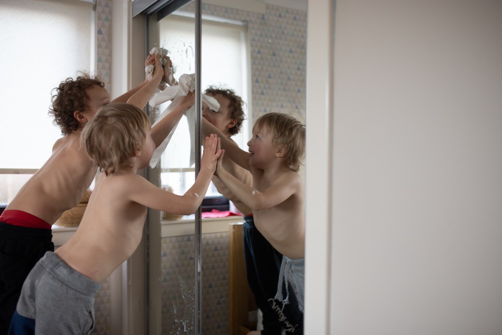 two boys cleaning window, in home family photoshoot