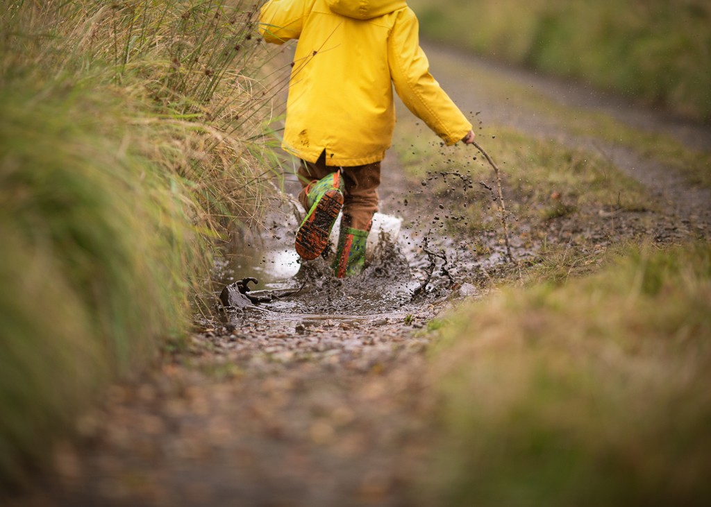 boy in yellow raincoat on the autumn walk playing in the muddle paddle, child portrait, fall outdoor photoshoot