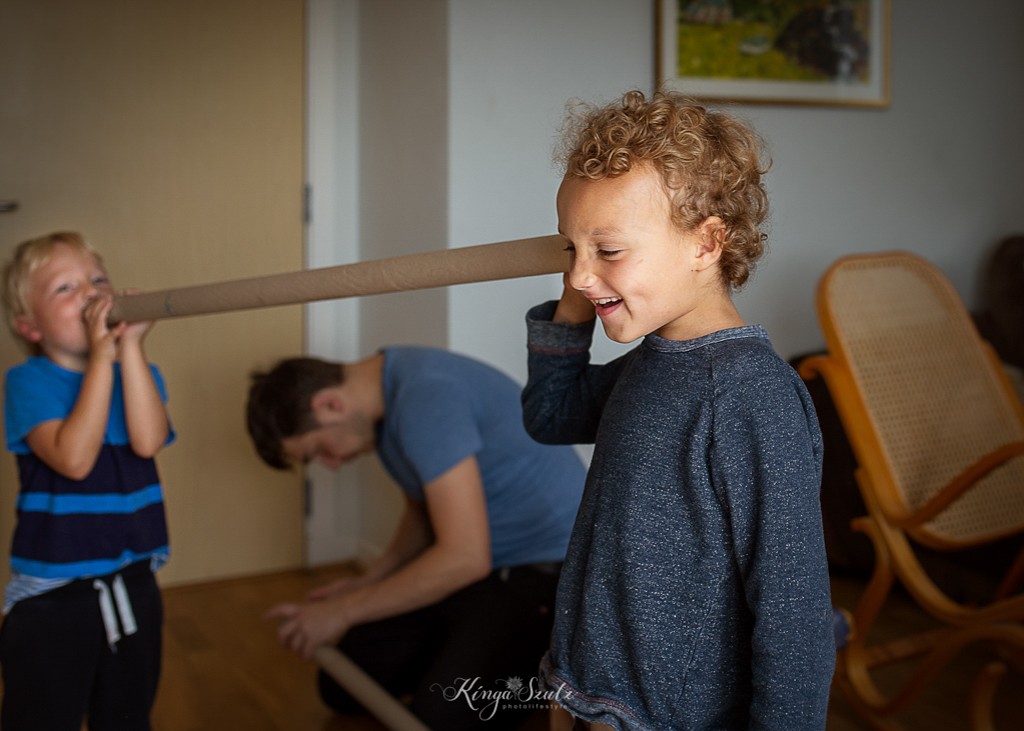 two boys and dad building cardboard craft, in home family photoshoot