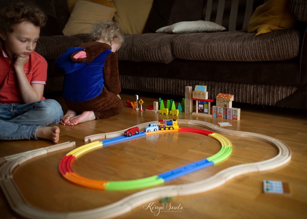 kids playing wooden train toys in living room, in home family photoshoot