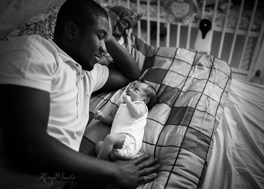 newborn baby girl with dad cuddling on the bed, in home newborn photoshoot