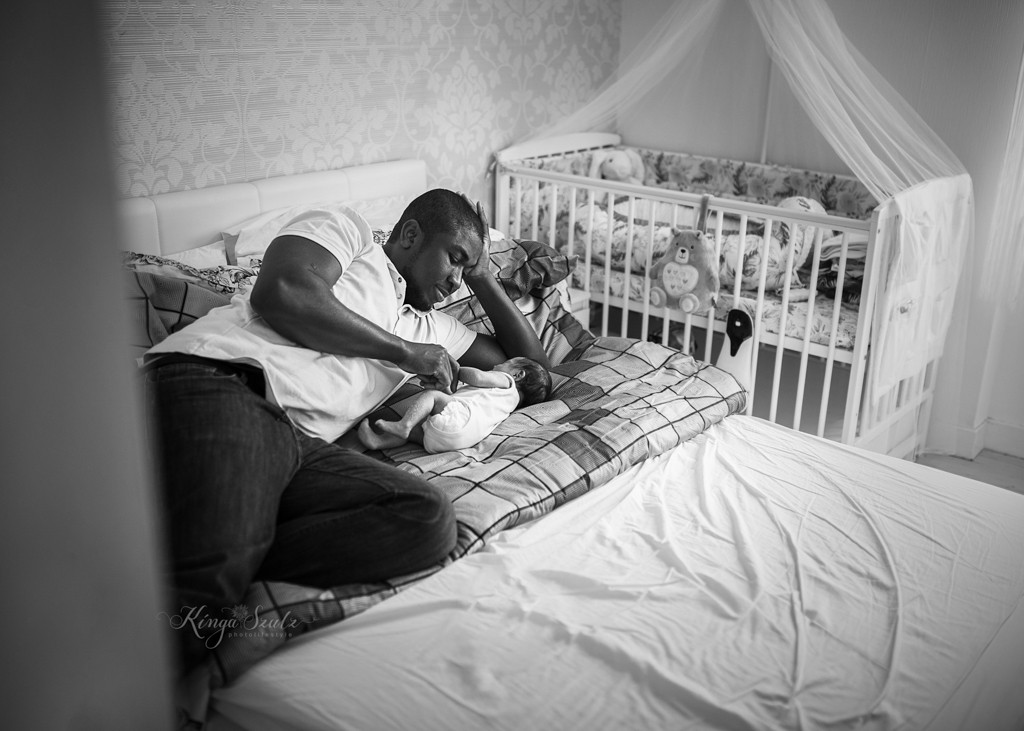 newborn baby girl with dad cuddling on the bed, in home newborn photoshoot