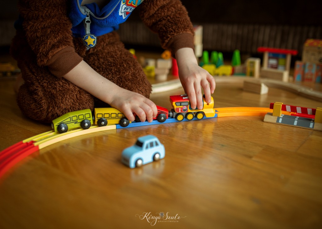 kids playing wooden train toys in living room, in home family photoshoot