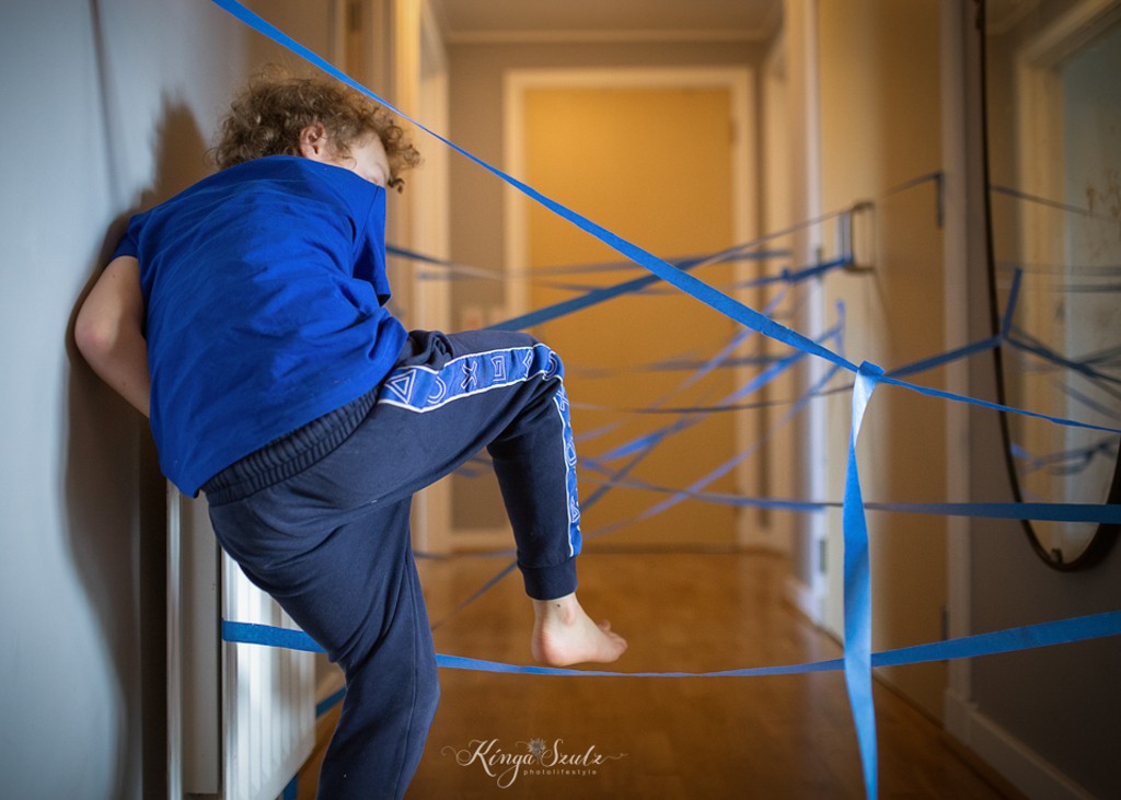 boy is playing laser maze in the hallway, in home Family photoshoot