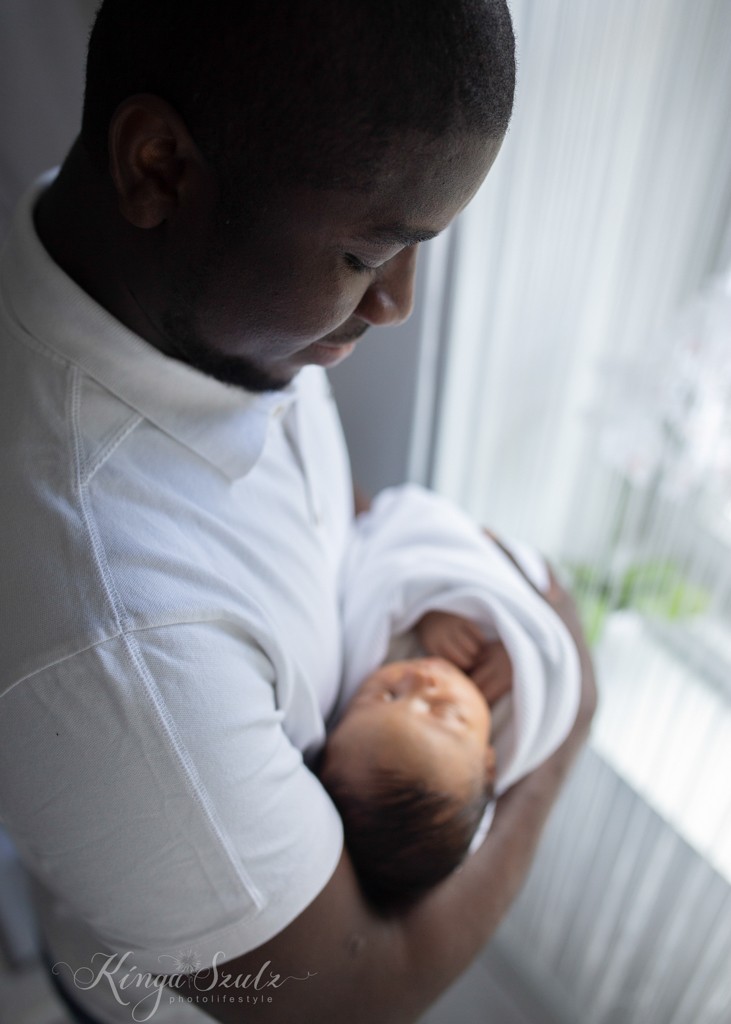 new baby girl wrapped in white blanker with dad, lifestyle newborn photoshoot at home