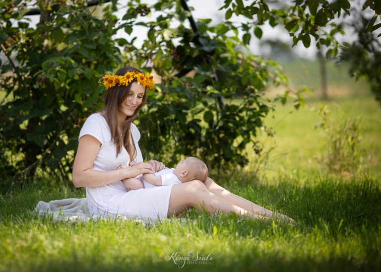 Mother cradling her newborn baby on a blanket in the garden during a summer outdoor newborn photoshoot in Glasgow