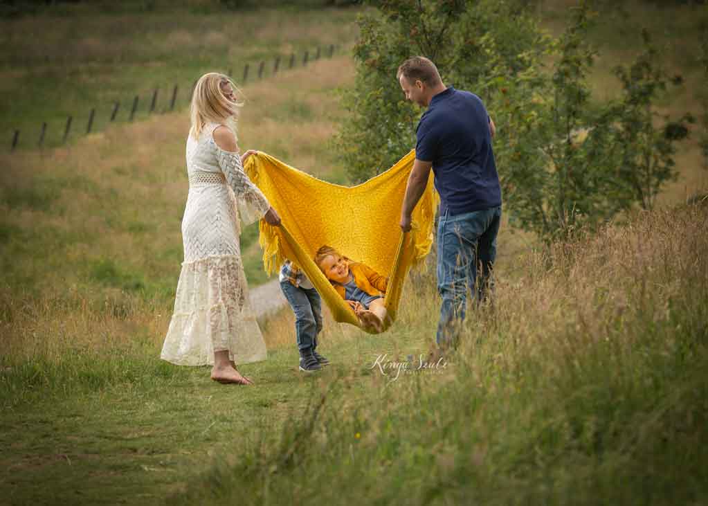 family with two kids playing blanket swing, fun-filled summer family photoshoot at Mugdock country park