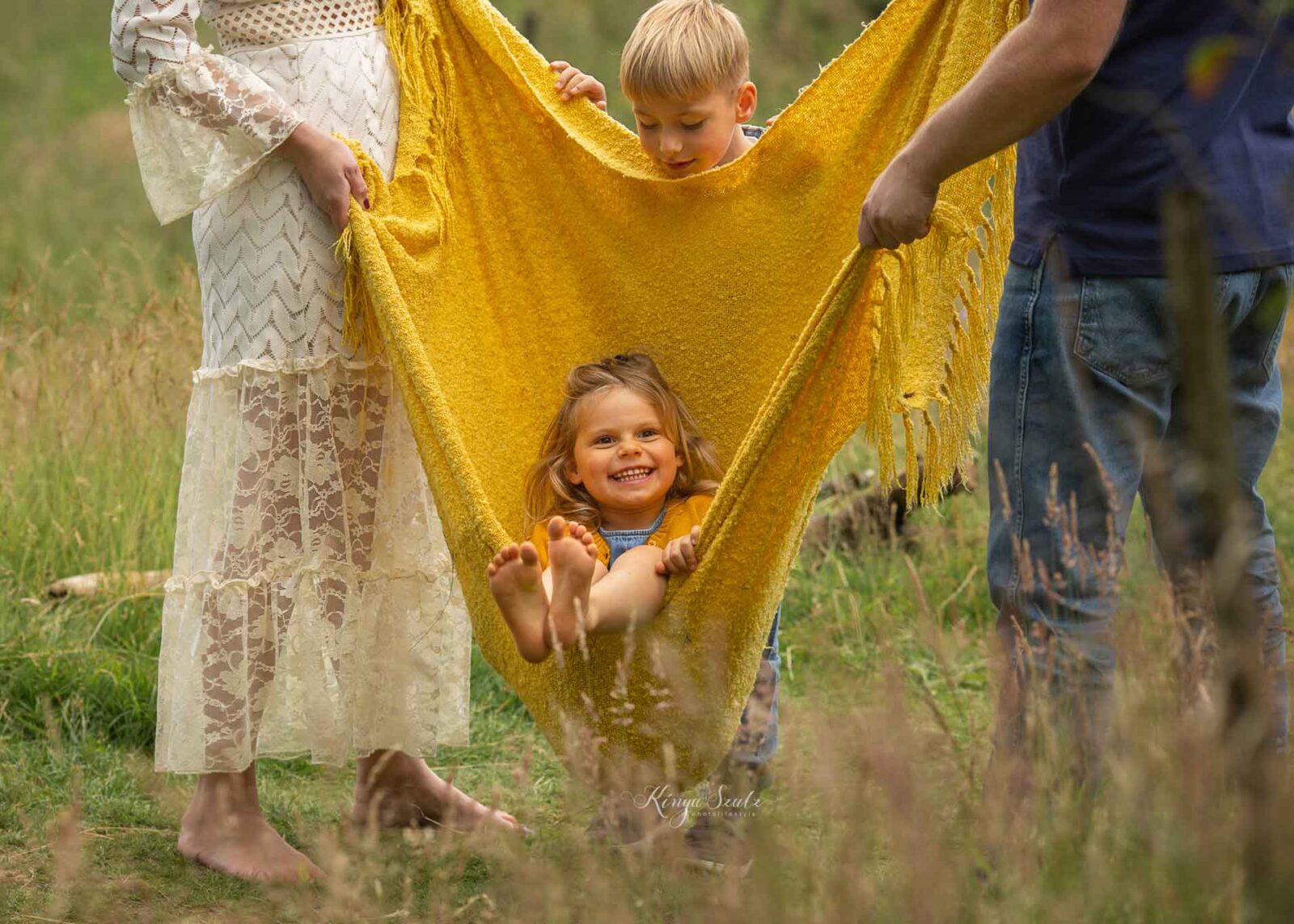 family with two kids playing blanket swing, fun-filled summer family photoshoot at Mugdock country park