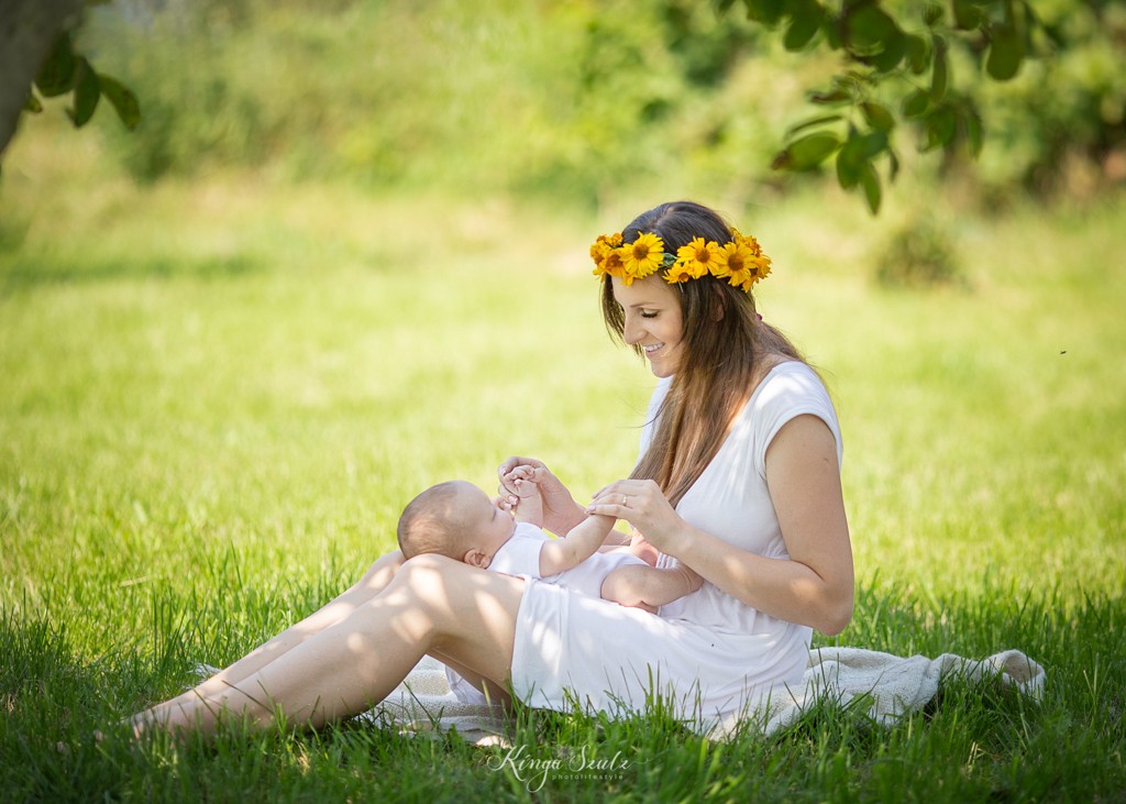 summer outdoor photoshoot in the garden round mother in white summer dress with newborn baby boy
