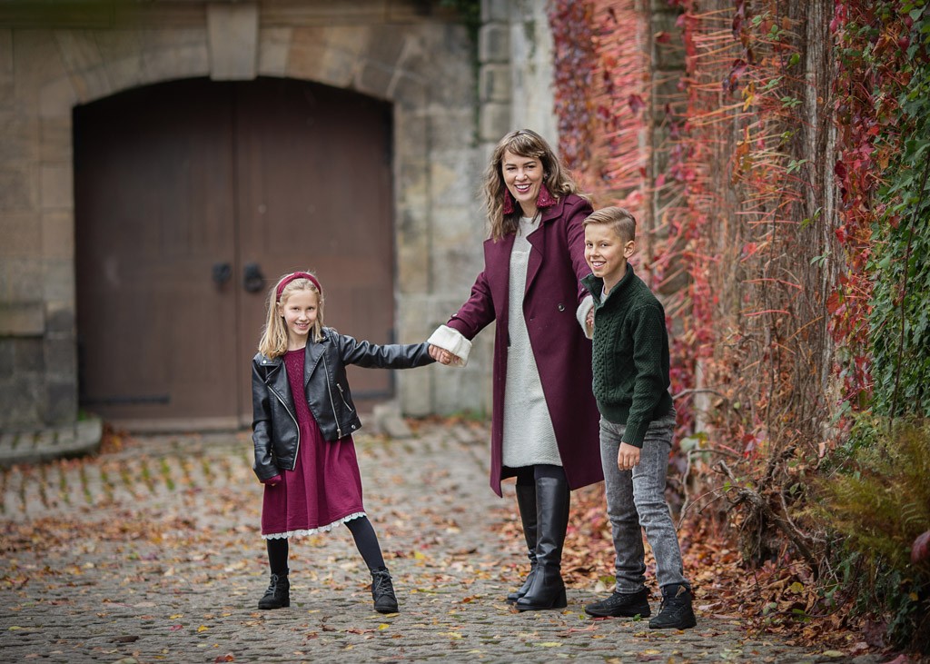 Mother with her son and daughter posing during an autumn family photoshoot in Glasgow, wearing coordinated burgundy, black, green and grey outfits