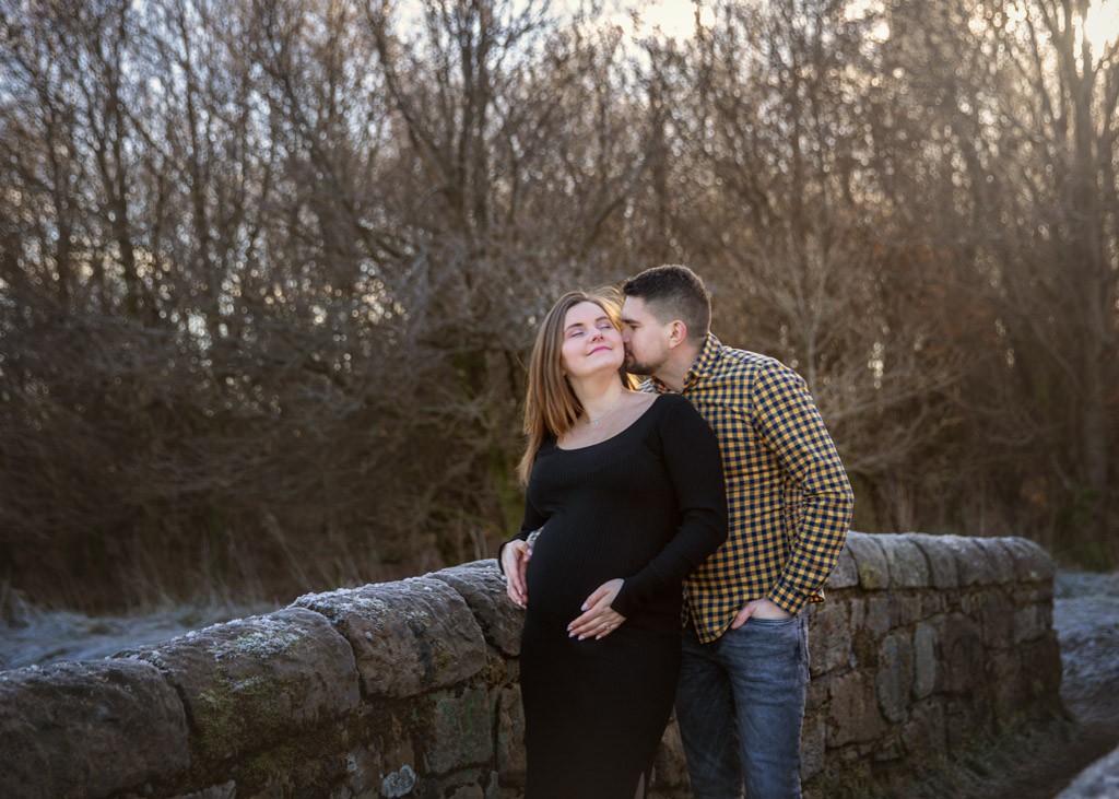 Baby bump, winter maternity photos of the pregnant couple at the stone bridge
