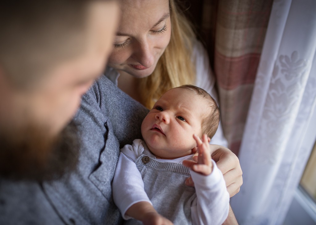 Mother holding her awake newborn baby during an at-home newborn photoshoot in Glasgow