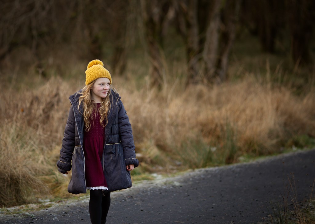 Young girl standing in frosty winter grass during an outdoor family photoshoot in Glasgow