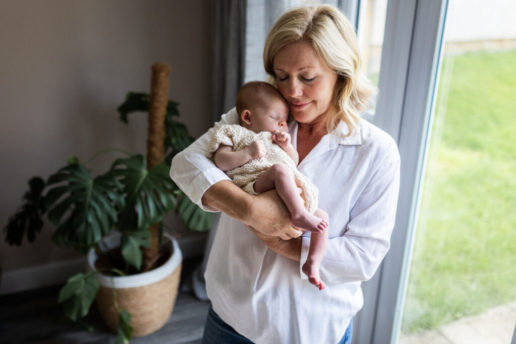 Grandmother holding her newborn granddaughter close and cuddling her during a family newborn session
