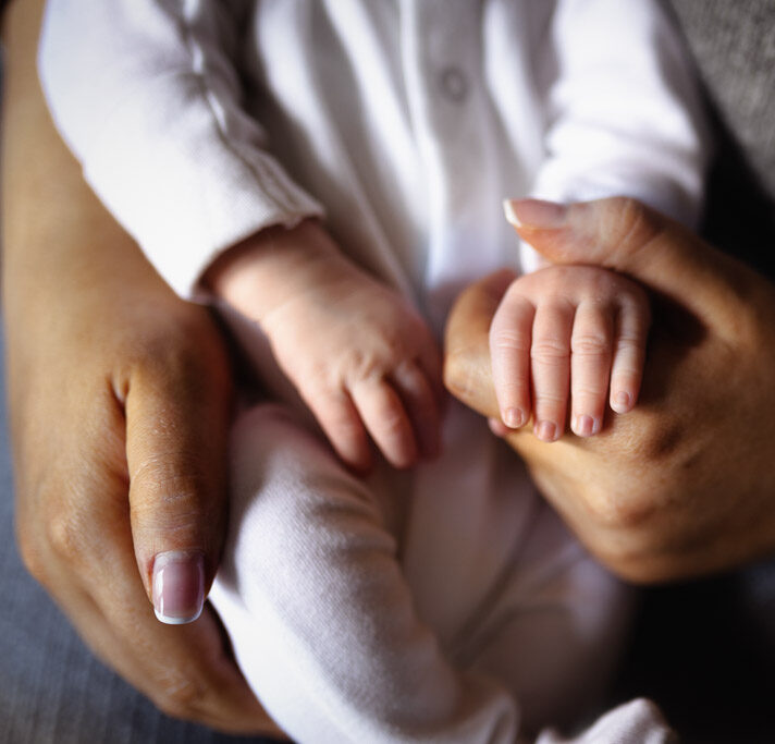 Close-up of tiny newborn fingers resting against a parent's hand during an intimate family moment