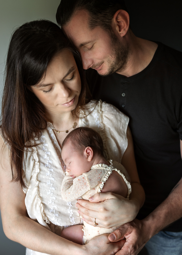 Mum and dad gently holding their newborn baby during an at-home newborn photoshoot in Glasgow