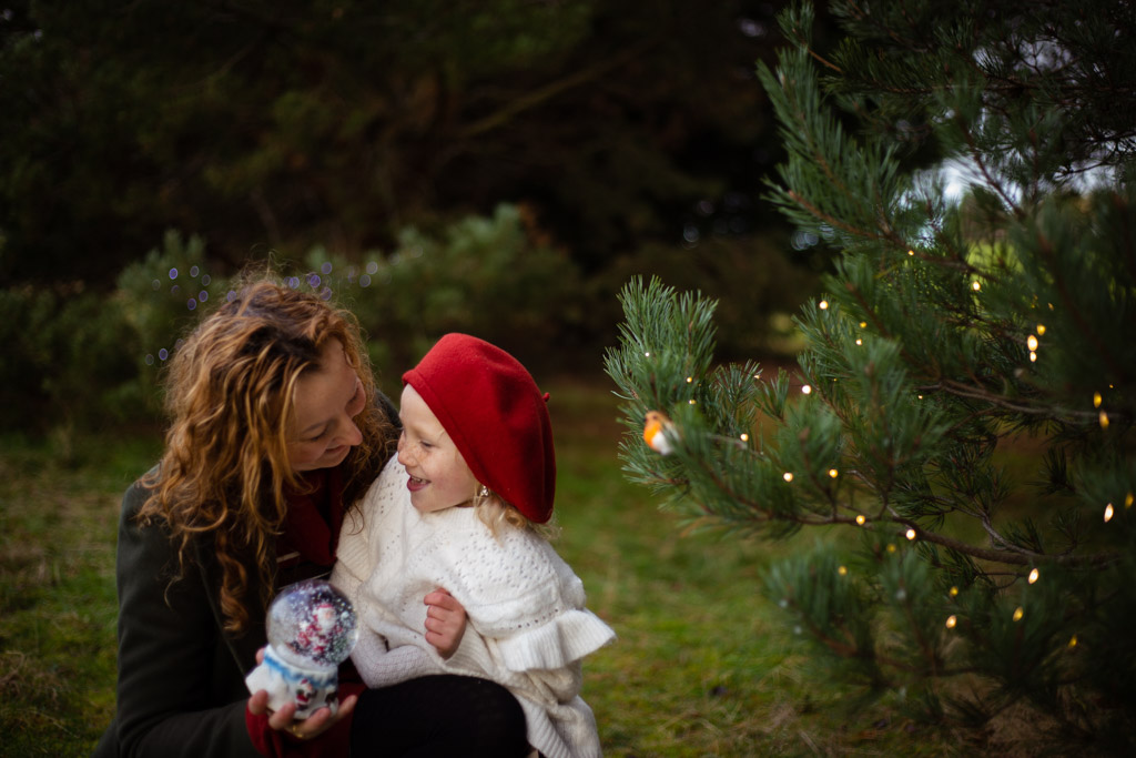 mother and daughter between Christmas tress, outdoor photoshoot