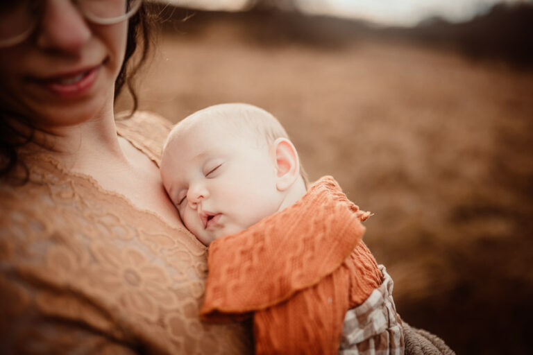 Sleeping newborn baby resting on his mother’s chest during a golden-hour outdoor newborn photoshoot in Glasgow