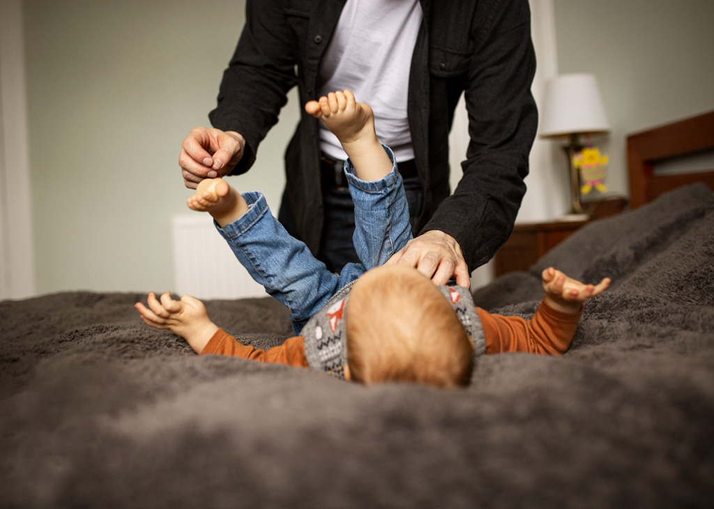 dad with son play on the bed during an at-home family photoshoot