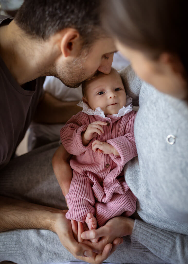 Parents holding and looking at their newborn baby during a relaxed newborn photoshoot at home in Glasgow