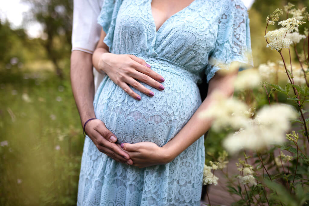 summer pregnancy photography featuring expectant parents embracing baby bump