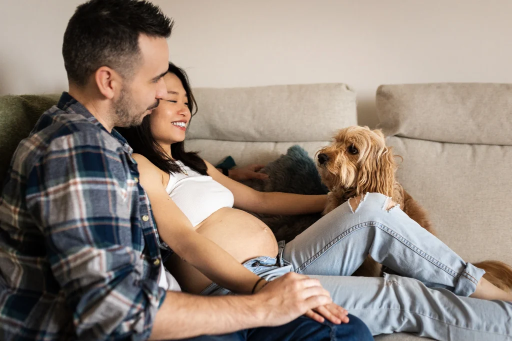 Pregnant woman relaxing on the sofa with her partner and their dogs during an at-home maternity photoshoot in Glasgow