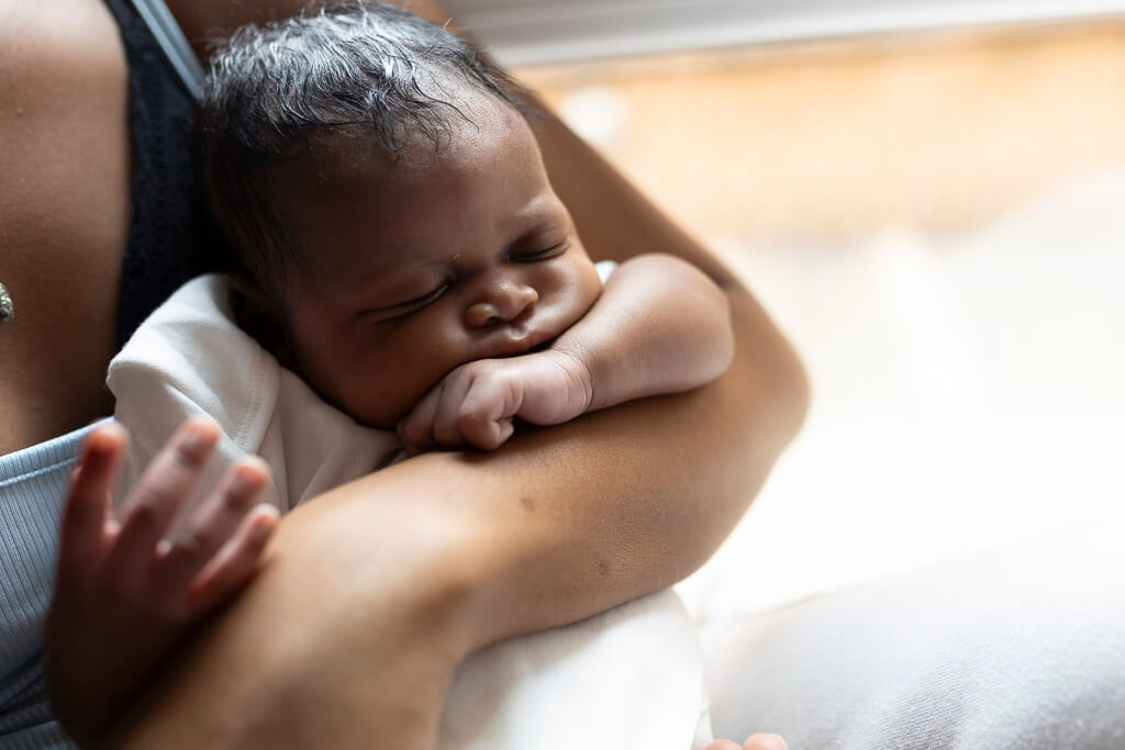 newborn baby sleeping in mother's arms during an in-home newborn photography session in Glasgow