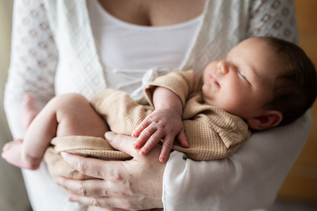 Newborn baby lying awake in mum's lap and looking up at her
