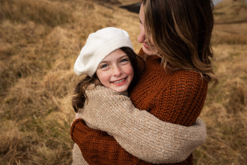 Mother and daughter holding hands during a relaxed family photoshoot in Scotland. Outdoor family photography capturing natural interaction, genuine smiles and meaningful family moments.