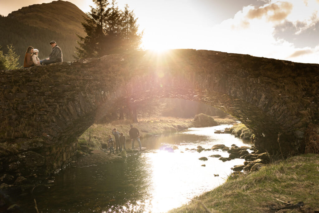 Family enjoying the winter landscape beside a historic stone bridge in Scotland