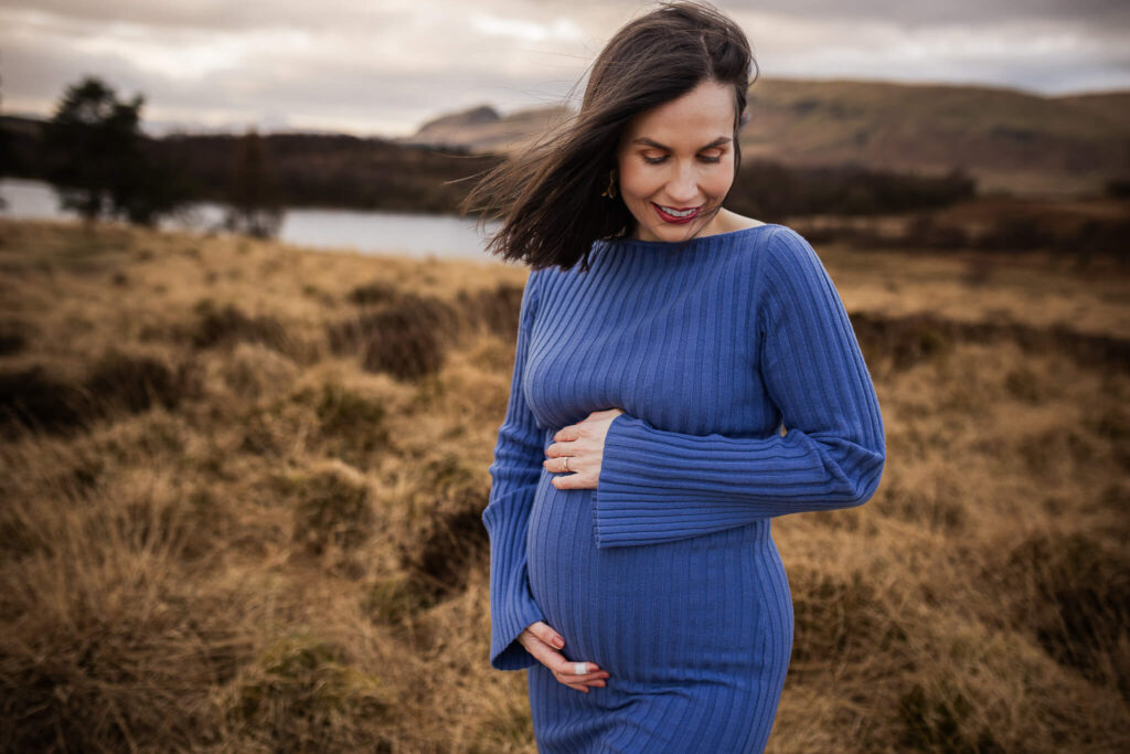 Pregnant woman looking down at and gently holding her bump during a maternity photoshoot in Glasgow