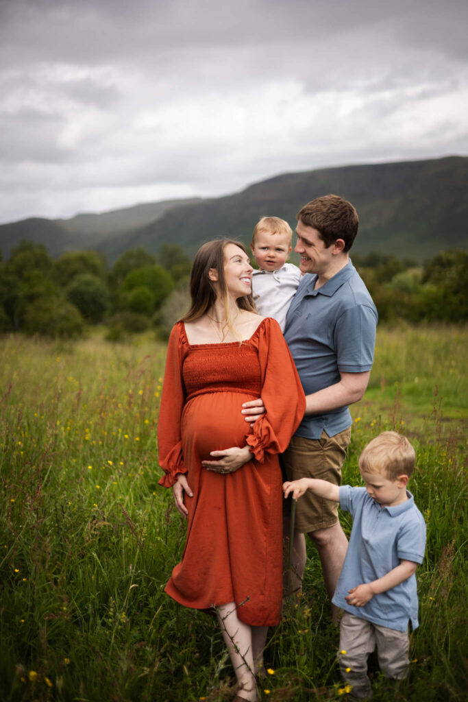 Family of four expecting their third child sharing a quiet moment together during an outdoor maternity session in Mugdock Country Park.