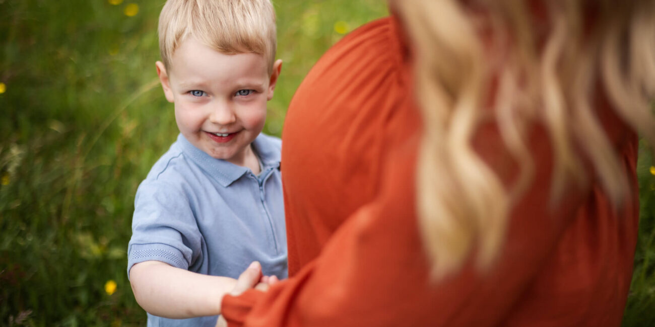 Young boy cuddling his mother's baby bump during a family maternity photoshoot in Scotland.