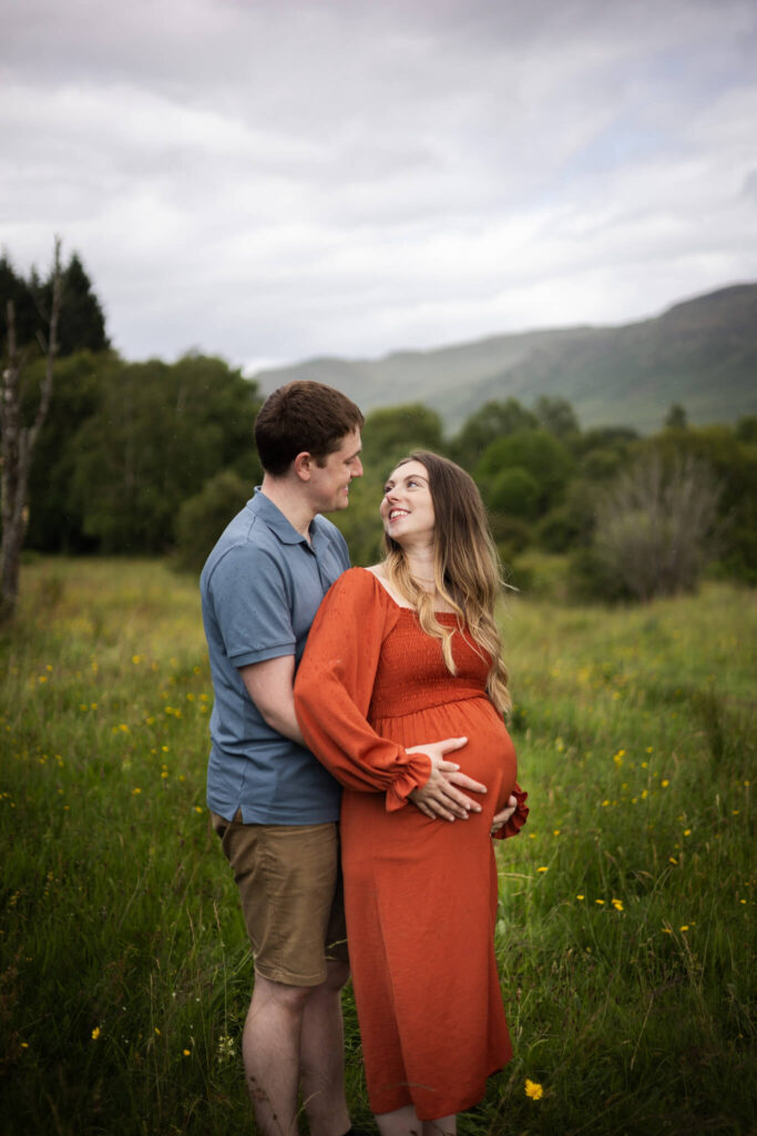 A couple expecting their third child sharing a quiet moment together during an outdoor maternity session in Mugdock Country Park.
