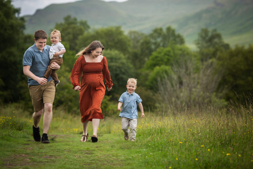 Family with two young children during an outdoor maternity photoshoot in Glasgow, wearing coordinated blue, orange and white outfits