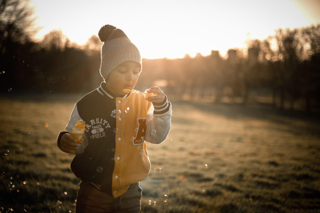 Boy blowing bubbles during an autumn outdoor family photoshoot at sunset in Glasgow