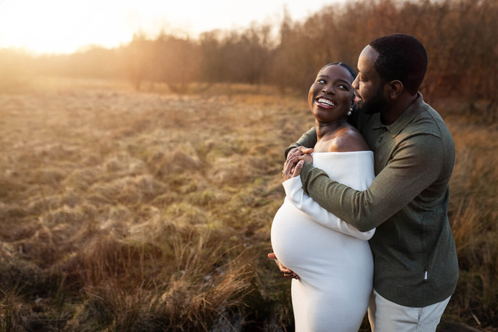 Expectant parents sharing an affectionate moment in Mugdock Country Park while celebrating their growing family.
